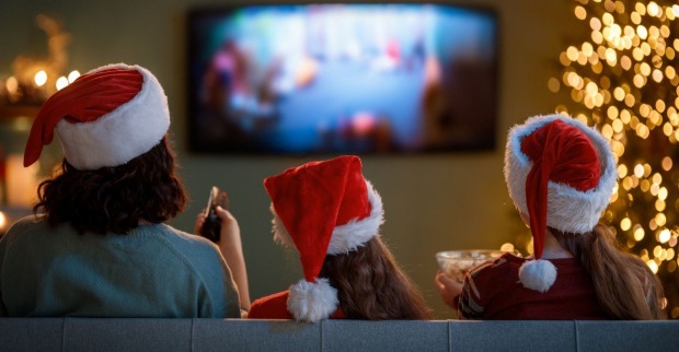 Drei Menschen mit Weihnachtsmütze sitzen auf einer Couch