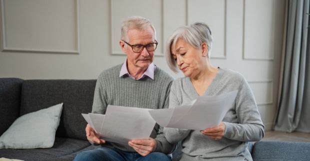 Älteres Paar prüft zu Hause gemeinsam Unterlagen zur Pension und privaten Altersvorsorge.