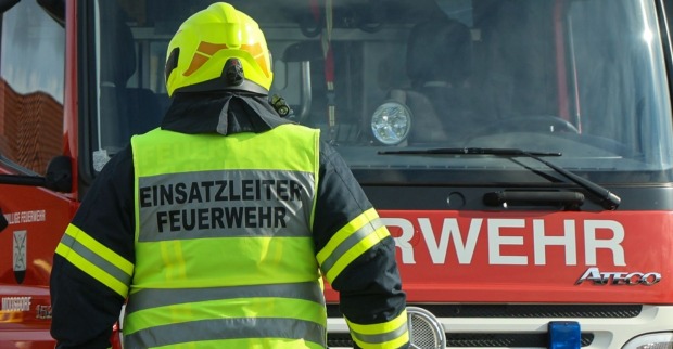 Einsatzleiter der Feuerwehr steht vor dem Feuerwehrauto
