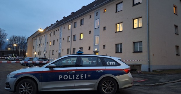 Ein Polizeiauto steht vor einem beleuchteten Wohnhaus.