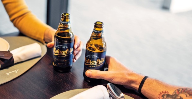 Zwei Menschen stoßen mit einer Flasche alkohlfreiem Mohrenbräu-Bier an.