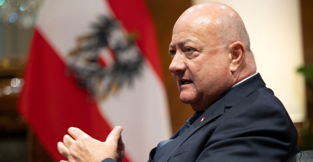 Österreichs Bundeskanzler Christian Stocker spricht im Bundeskanzleramt, im Hintergrund die österreichische Flagge.