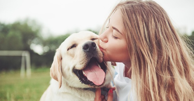 Junge attraktive Frau küsst ihren Hund | Credit: iStock.com/standret