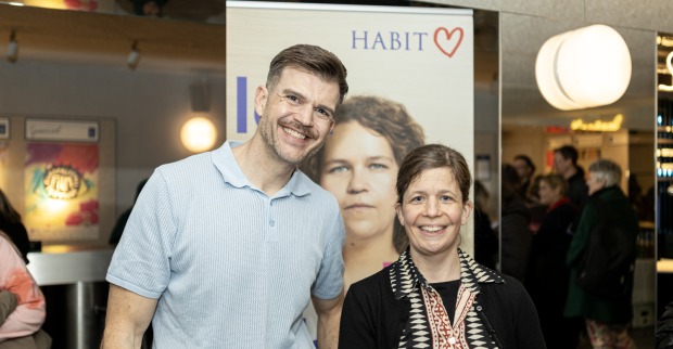 Mann und Frau im Stadtkino vor einem Aufsteller des Hauses der Barmherzigkeit