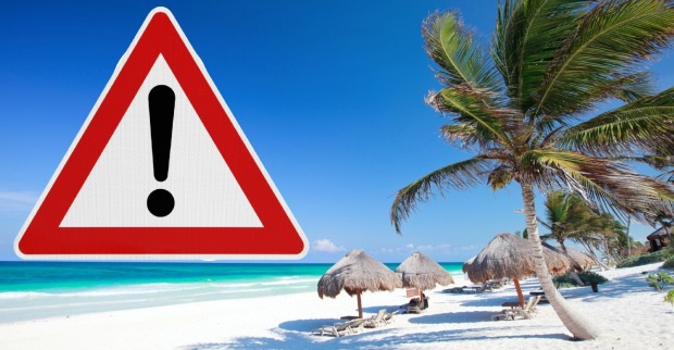 Warnschild mit Ausrufezeichen am Strand von Mexiko – Symbolbild für aktuelle Reisewarnungen und Sicherheitswarnung nach Unruhen im Land.