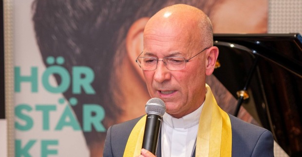 Dompfarrer Toni Faber mit Mikrophon in der Hand/ Dompfarrer Toni Faber spricht über seine Schock-Diagnose in der Jugend.