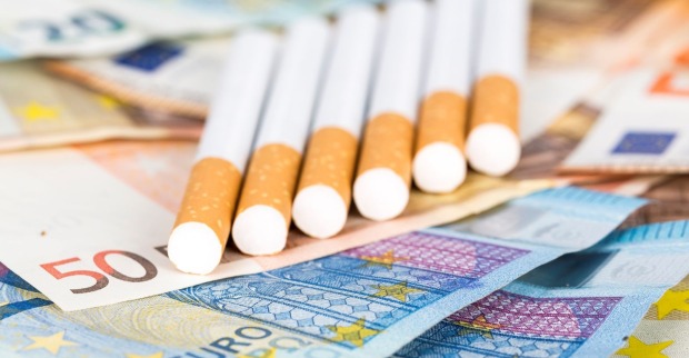 Mehrere Zigaretten liegen auf Euro-Banknoten und symbolisieren die steigenden Tabakpreise in Österreich im März 2026.