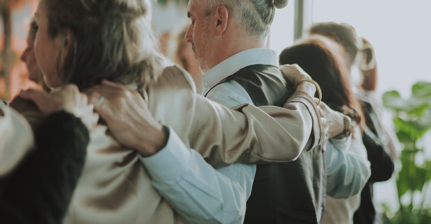 Teilnehmende einer Achtsamkeitsübung stehen Arm in Arm zusammen | Credit: Tassilo Edelsbacher