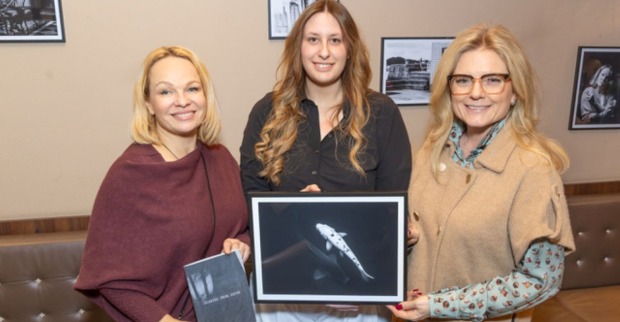 Drei Frauen mit einem Foto der Ausstellung im Café Hummel