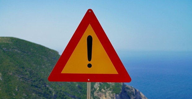 Warnschild vor einer Küste.