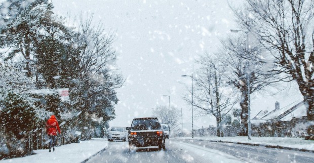 Schnee in Österreich: Winterliches Wetter mit starkem Schneefall auf einer Straße, Autos fahren durch verschneite Landschaft