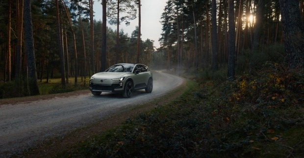 Der Volvo EX60 fährt auf einer Straße im Wald.