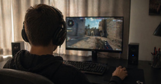 Jugendlicher mit Kopfhörern spielt Videospiel am PC, während ein Amoklauf an einer Schule im Chat angekündigt wurde