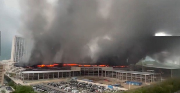 Großbrand iBYD Brand Parkhaus in Shenzhen mit meterhohen Flammen und schwarzer Rauchentwicklung über einem Parkhauskomplex