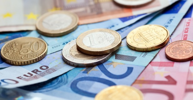 Geldmünzen und Banknoten auf einem Tisch dargestellt.