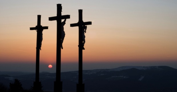 Kreuzigung Jesu auf Golgotha mit drei Kreuzen bei Sonnenuntergang; Themenbild für Karfreitag Bedeutung, Rituale und Traditionen.