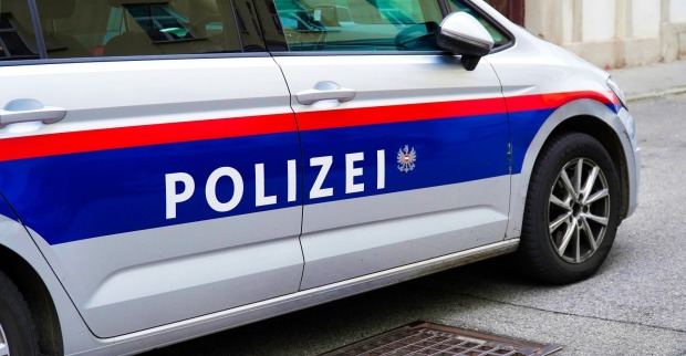 Ein Polizeiauto in Österreich Wien ist in einer ruhigen Straße in einer europäischen Stadt in der Nähe eines Abflusses abgestellt.