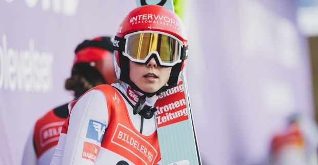 Lisa Eder steht auf einer Skisprungschanze und sieht nachdenklich in die Ferne