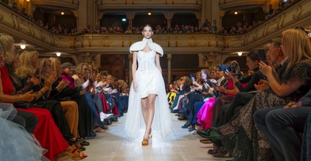 Model geht in einem weißen Kleid über den Laufsteg