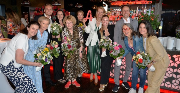 Mehrere Personen halten Blumensträuße in den Händen und lächeln in die Kamera