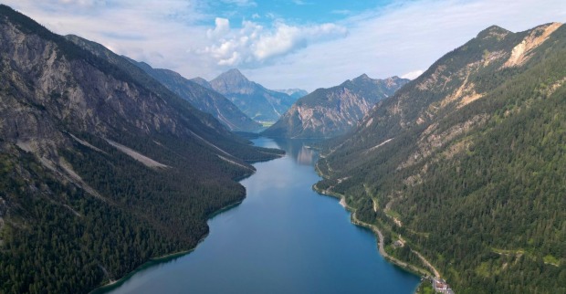 Der tiefblaue, fjordähnliche Plansee in Tirol umgeben von den bewaldeten Hängen der Alpen