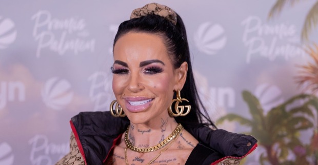 Gina-Lisa Lohfink bei einem öffentlichen Event mit schwarzen Haaren, auffälligem Make-up und goldenen Accessoires. Die Reality-TV-Bekanntheit sorgt aktuell wegen ihrer schweren Gesundheitskrise für Schlagzeilen.