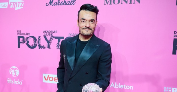 Giovanni Zarrella posiert bei einer Musikveranstaltung auf dem roten Teppich vor pinkem Hintergrund und sorgt nach Kritik von Ex-Bro’Sis-Kollege Faiz Mangat für Schlagzeilen.