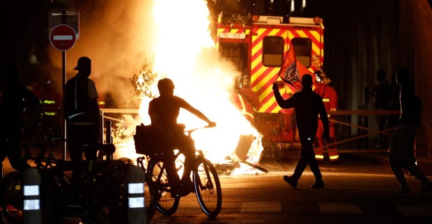 Ausschreitungen in Paris nach CL-Finale: Brennendes Feuer, Einsatzkräfte und Personen auf der Straße während gewaltsamer Unruhen in der Nacht