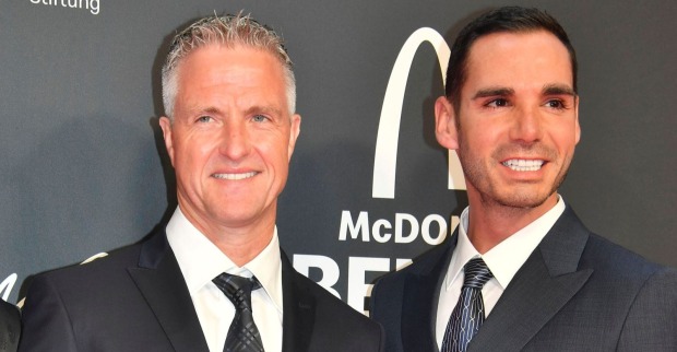 Ralf Schumacher und sein Verlobter Étienne Bousquet-Cassagne posieren elegant im Anzug auf einem roten Teppich. Kurz vor ihrer Hochzeit in Saint-Tropez sorgt eine geplante Beauty-OP für Schlagzeilen.