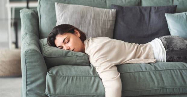 Erschöpfte junge Frau ruht zu Hause auf Couch | Credit: sebra/Shutterstock