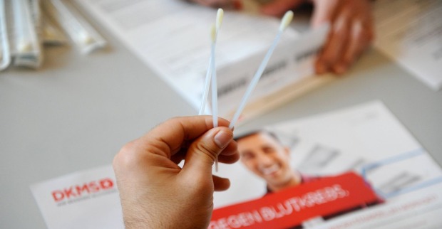 Mensch hält zwei lange Wattestäbchen in der Hand