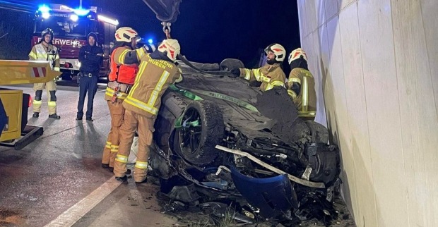 Einsatzkräfte der Feuerwehr arbeiten an einem zerstörten Auto, das nach einem Unfall in Längenfeld auf dem Dach liegt