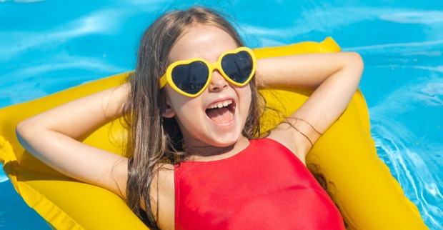 Ein Mädchen liegt in einem Pool auf einer gelben Luftmatratze.