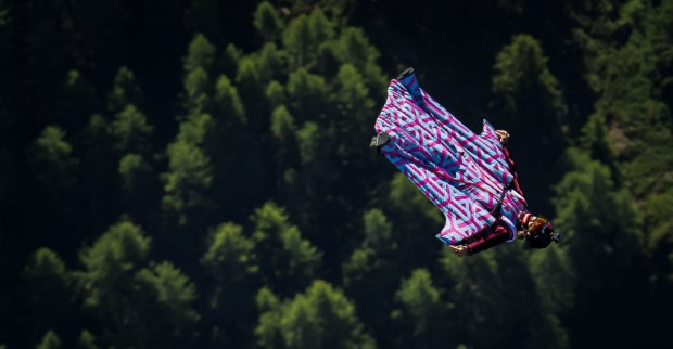 Frau fliegt in einem Wingsuit über einen Wald