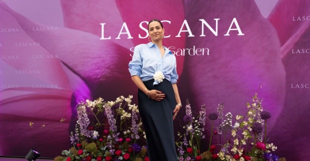Amira Aly steht lächelnd und mit rundem Babybauch auf einem violetten Teppich auf der Lascana-Gala in Hamburg