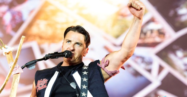 Andreas Gabalier bei einem Live-Auftritt auf der Bühne. Der Volks-Rock’n’Roller singt ins Mikrofon und jubelt mit erhobener Faust vor seinem Publikum.