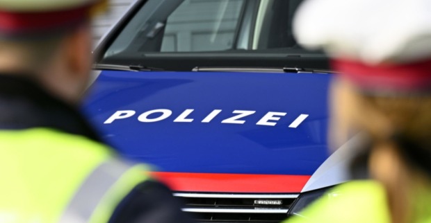 Zwei Polizisten stehen vor einem Polizeiauto