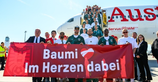 Mehrere Menschen stehen vor einem Flugzeug und halten ein Transparent hoch