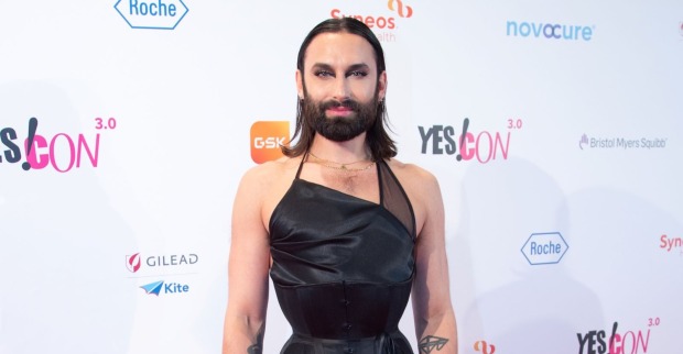 Conchita Wurst alias Tom Neuwirth posiert auf dem roten Teppich bei einem Event. Der Sänger trägt ein schwarzes Outfit und blickt in die Kamera.