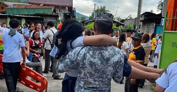 Rettungskräfte tragen verletzte Person nach Erdbeben auf den Philippinen durch Menschenmenge nach Tsunami-Warnung
