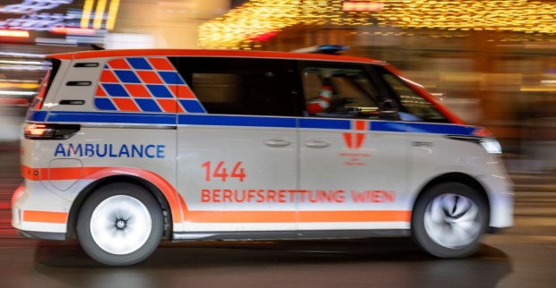 Ein Rettungswagen der Berufsrettung Wien fährt mit eingeschaltetem Blaulicht auf einer städtischen Straße.