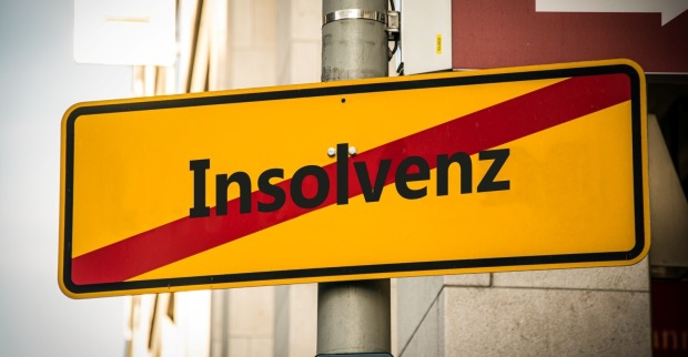 Ein Bild mit einem Wegweiser, der in zwei verschiedene Richtungen zeigt. Eine Richtung weist auf einen Neuanfang hin, die andere auf einen Bankrott.