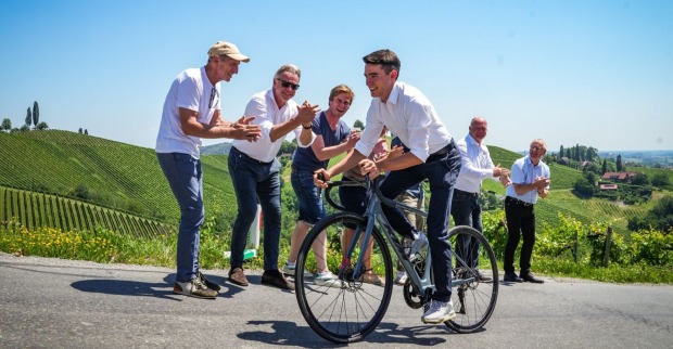 Ein Mann fährt auf einem Rad einen Berg hoch, während Zuschauer klatschen