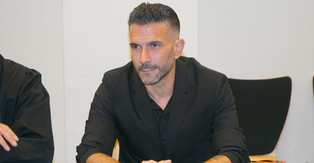 Marc Terenzi sitzt bei einer Veranstaltung in einem schwarzen Anzug an einem Tisch und blickt konzentriert nach vorne.
