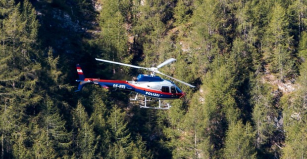 Polizeihubschrauber im Einsatz über einem Waldgebiet.