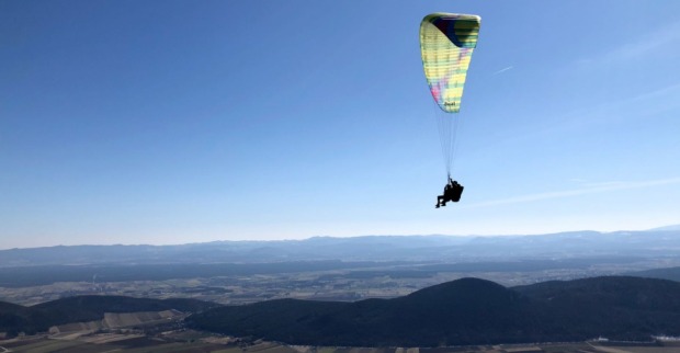 Paragleiter fliegt über eine Berglandschaft