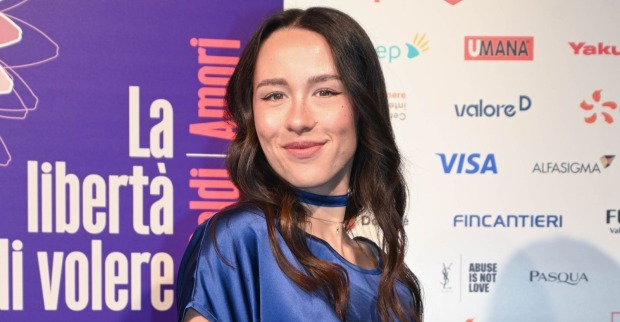 Aurora Ramazzotti lächelt bei einem öffentlichen Auftritt in einem blauen Kleid in die Kamera. Nach ihrer Hochzeit auf Sizilien sorgten Ätna-Ausbruch und Flugchaos für Schlagzeilen.