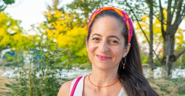 Caroline Athanasiadis lächelt im Freien mit buntem Haarband nach ihrer Operation