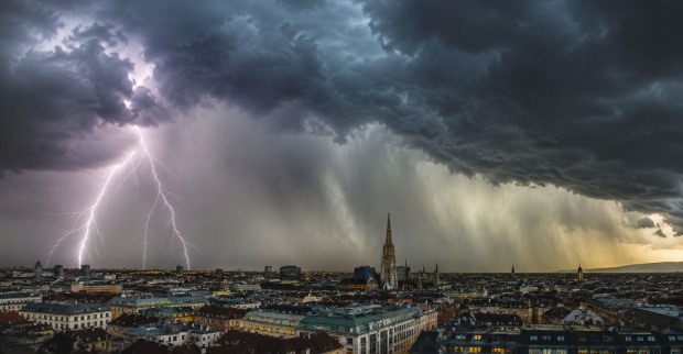 Gewitterfront mit Blitz, Starkregen und dunklen Wolken über einer Stadt in Österreich, Unwetter mit Hagel und Sturm zieht auf