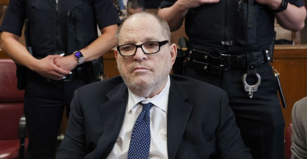 Harvey Weinstein sitzt während eines Gerichtstermins im Anzug vor Polizisten. Der Ex-Hollywood-Produzent wurde nach einem Herzversagen aus dem Gefängnis ins Krankenhaus gebracht.
